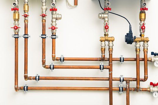 A bunch of copper pipes are connected to a wall.