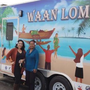 Two women are standing in front of a trailer that says waan lom.