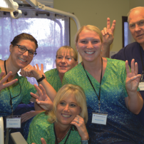 A group of nurses are posing for a picture in a dental office.