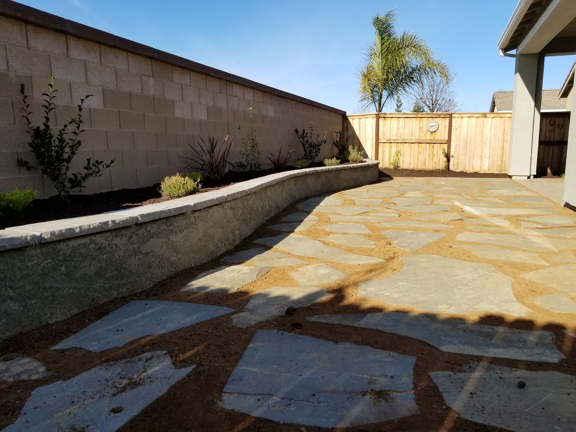 A patio with a brick wall and a wooden fence in the background