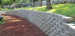 A stone wall is in the middle of a lush green yard.