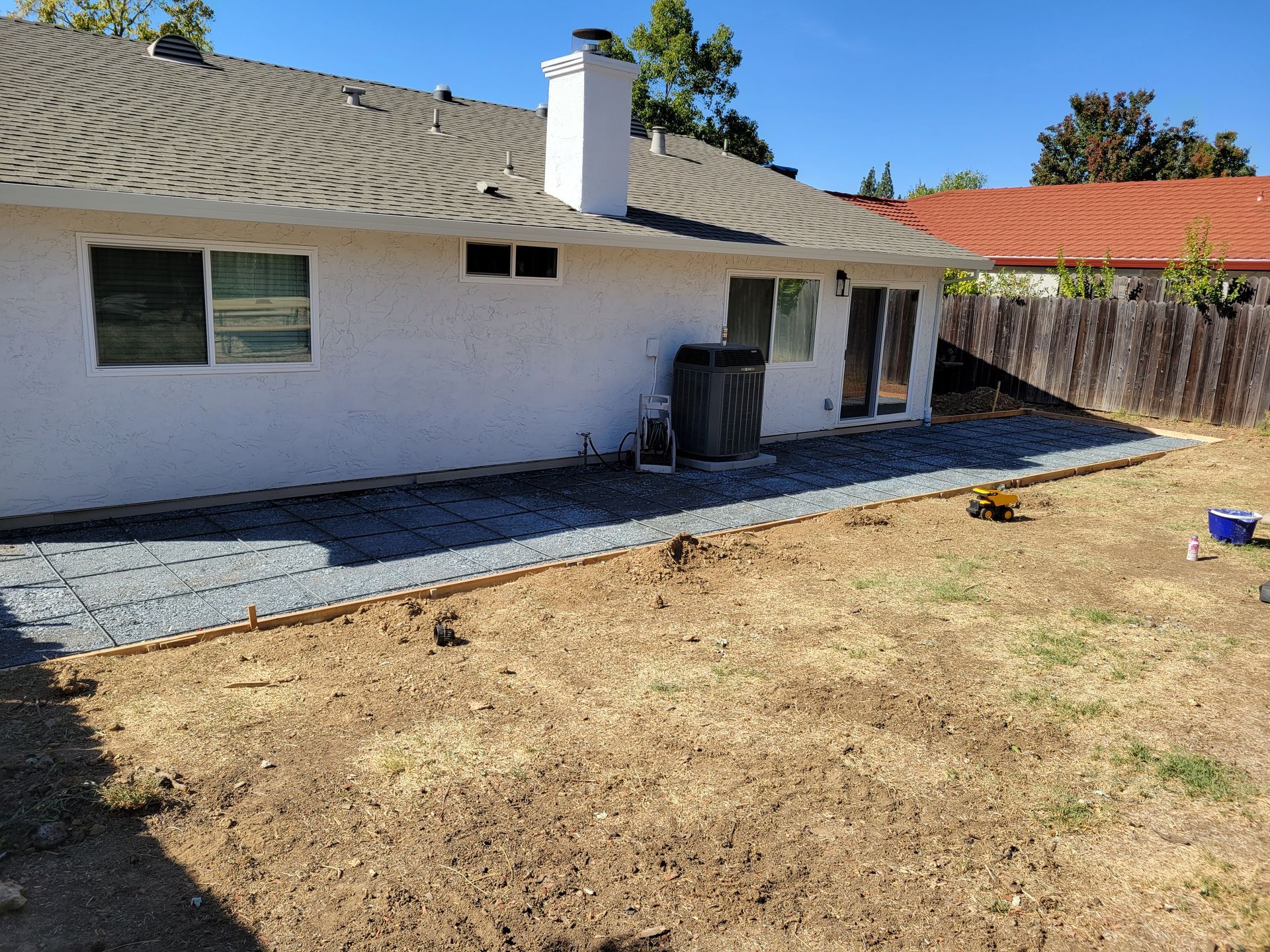 The backyard of a house with a patio and a fence.