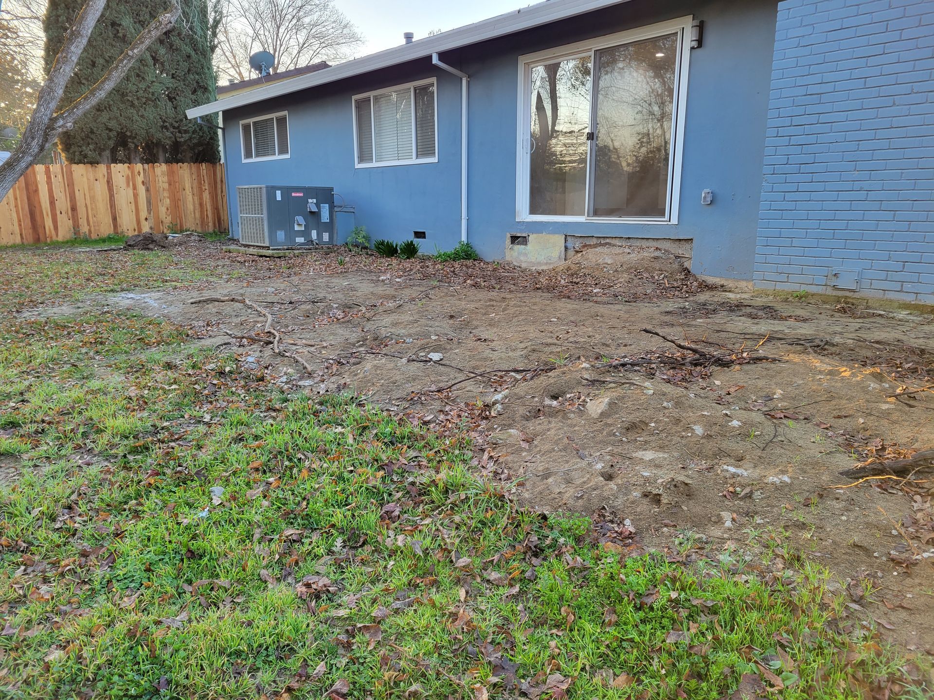 A blue house with a sliding glass door and a fence in the backyard.
