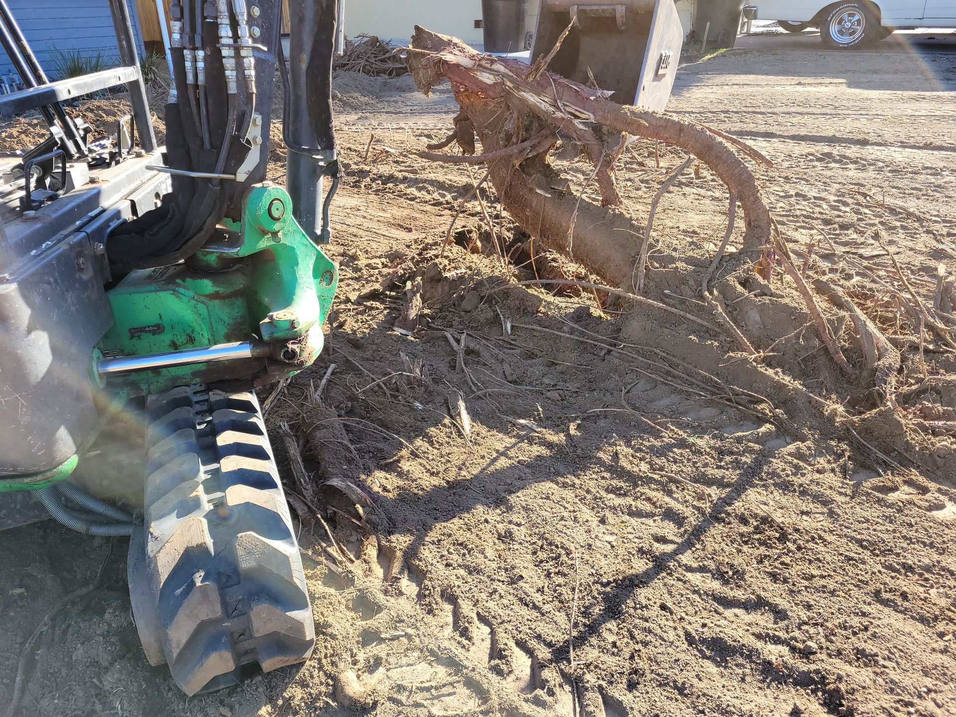 A green tractor is sitting on top of a dirt field.