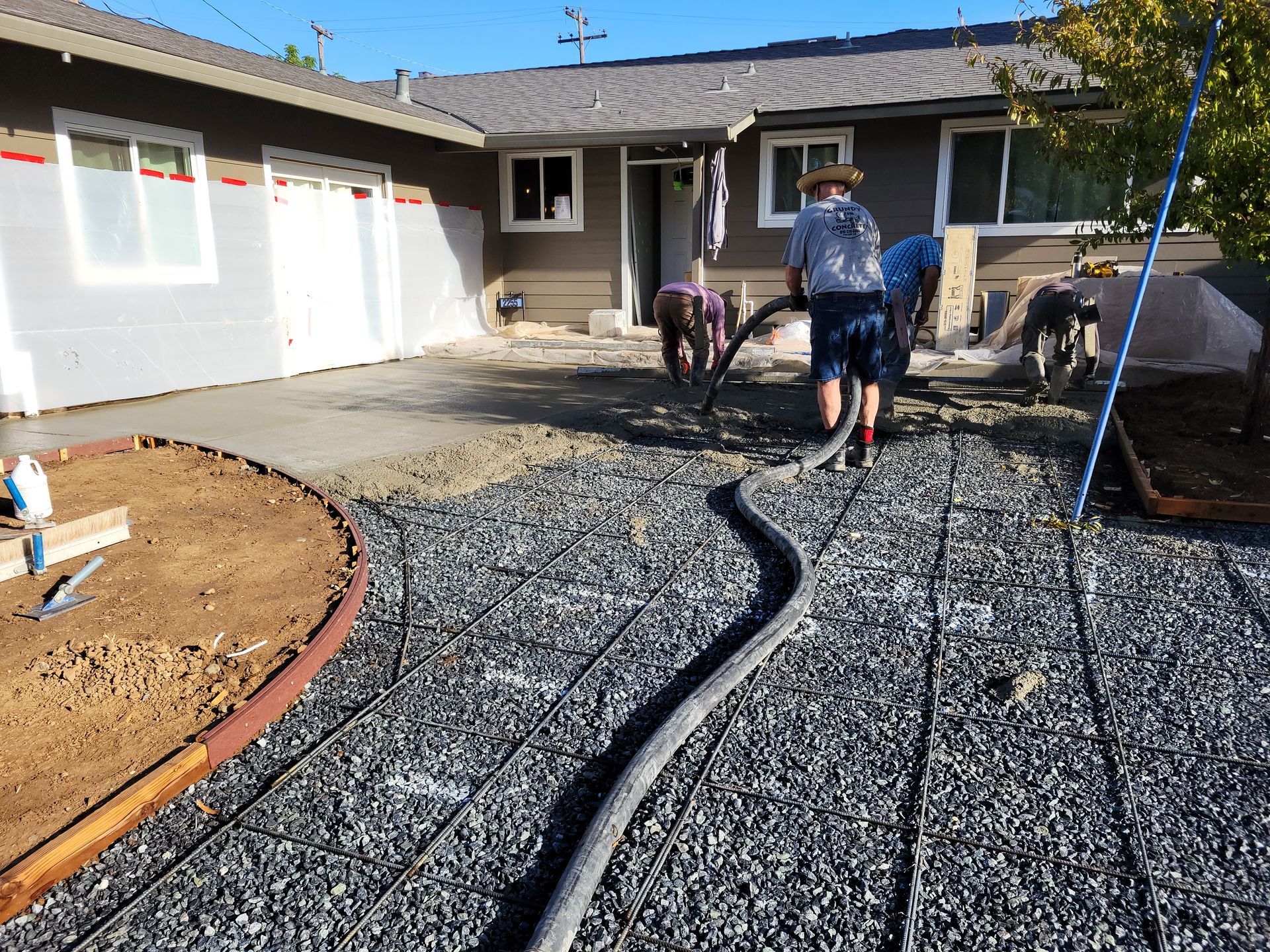 A group of people are working on a driveway in front of a house.