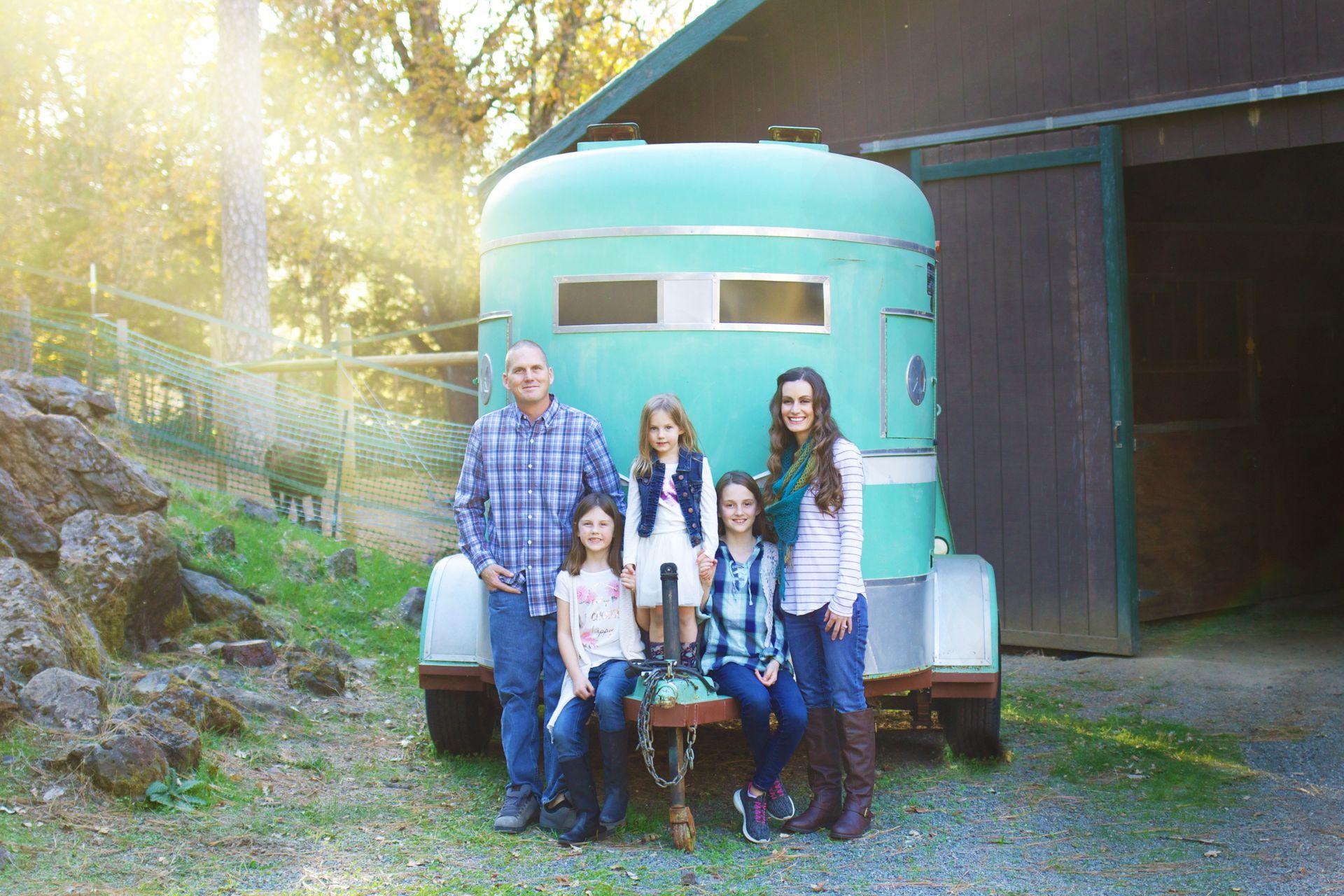 A family is posing for a picture in front of a horse trailer.