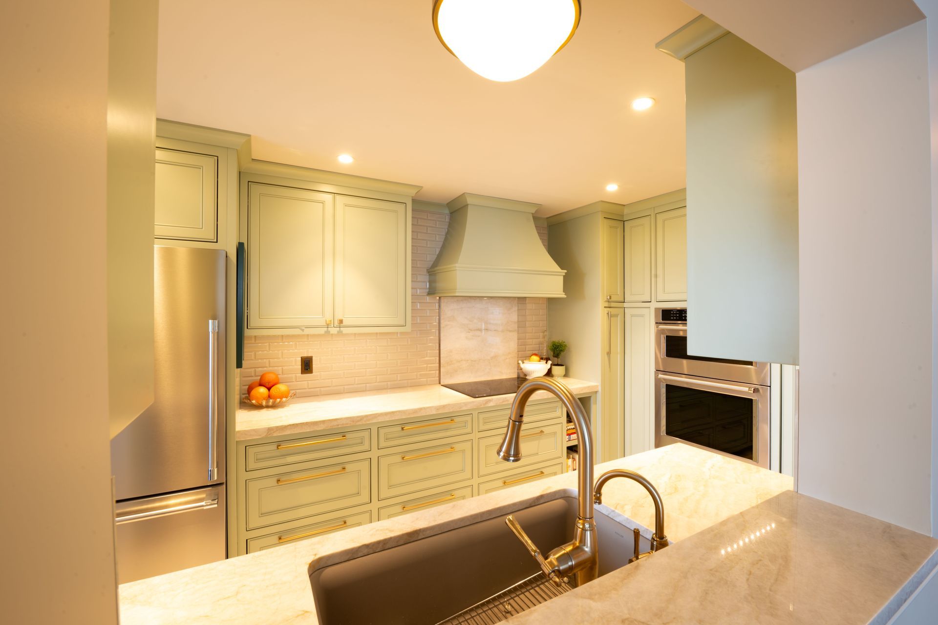 Kitchen with light green cabinets, stainless steel appliances, and a marble countertop.