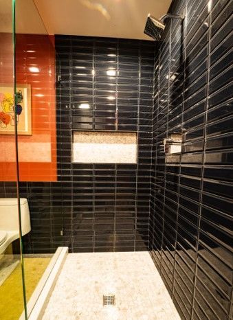A bathroom with black tiles and a walk in shower.