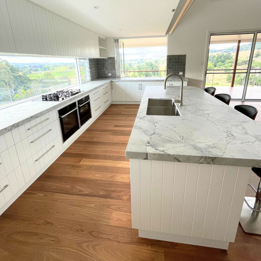A Kitchen With White Cabinets, Marble Counter Tops, Wooden Floors, And A Large Island — Ben Lynch Cabinetmaking in
Ballina, NSW