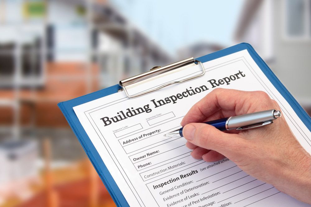 A Person Is Writing On A Building Inspection Report On A Clipboard — Firewerx In Dubbo, NSW