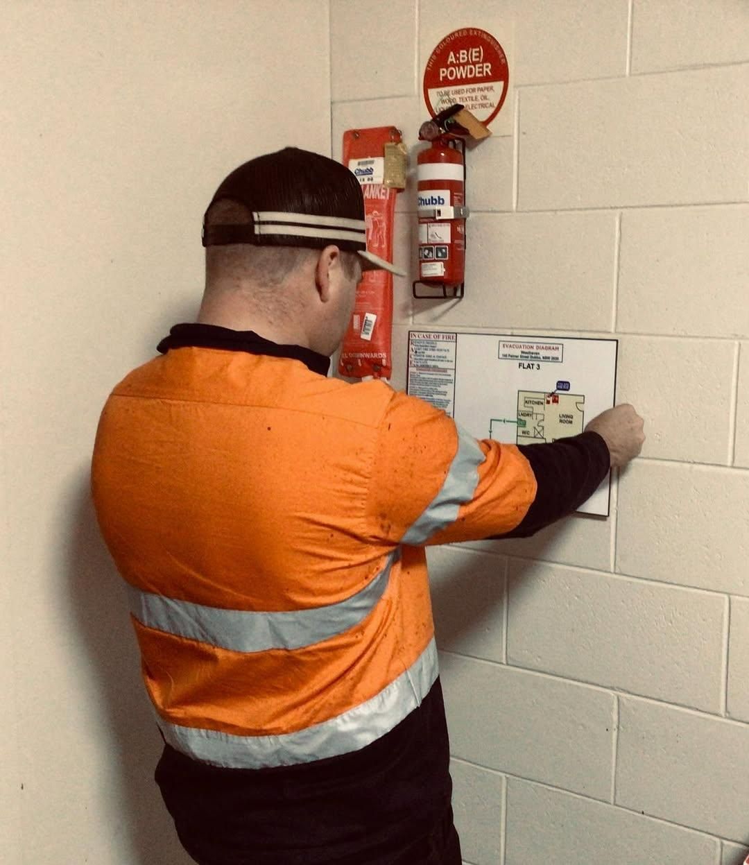 A Man in An Orange Safety Vest Is Writing on A Piece of Paper — Firewerx In Dubbo, NSW