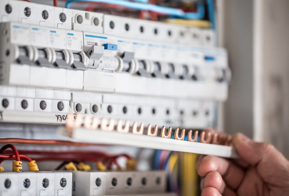 A Person Is Holding A Wire In Front Of An Electrical Box — Firewerx In Forbes, NSW