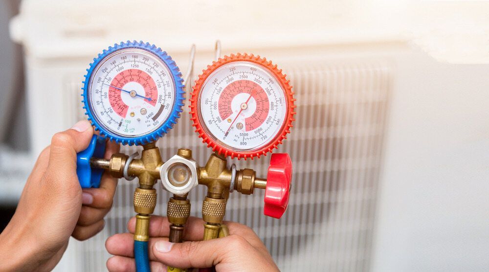 A Person Is Holding Two Gauges In Their Hands In Front Of An Air Conditioner — Firewerx In Bathurst, NSW