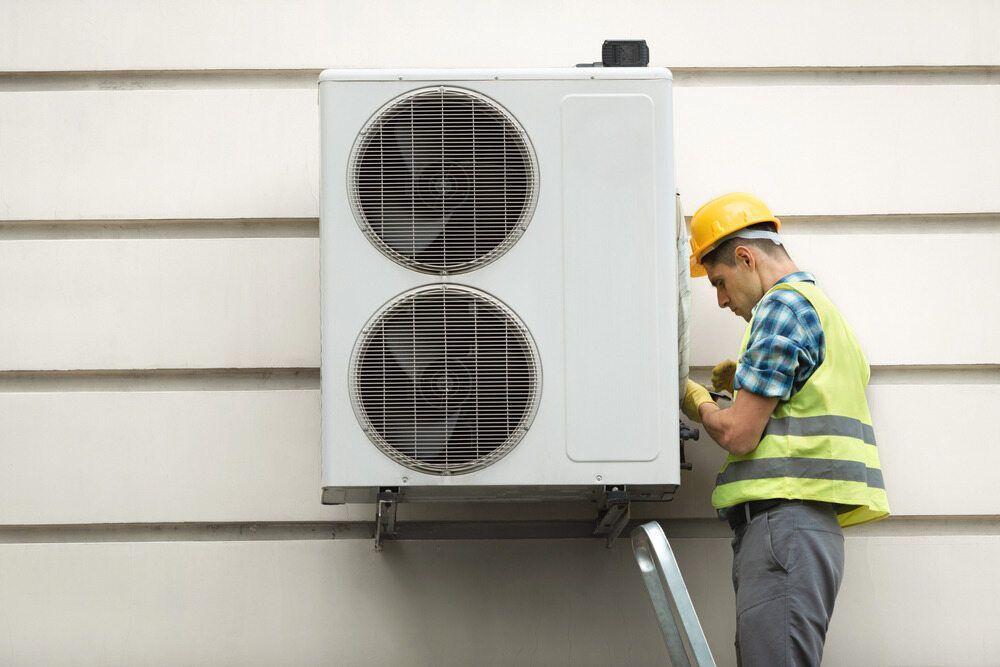 A Man Is Installing An Air Conditioner On The Side Of A Building — Firewerx In Forbes, NSW