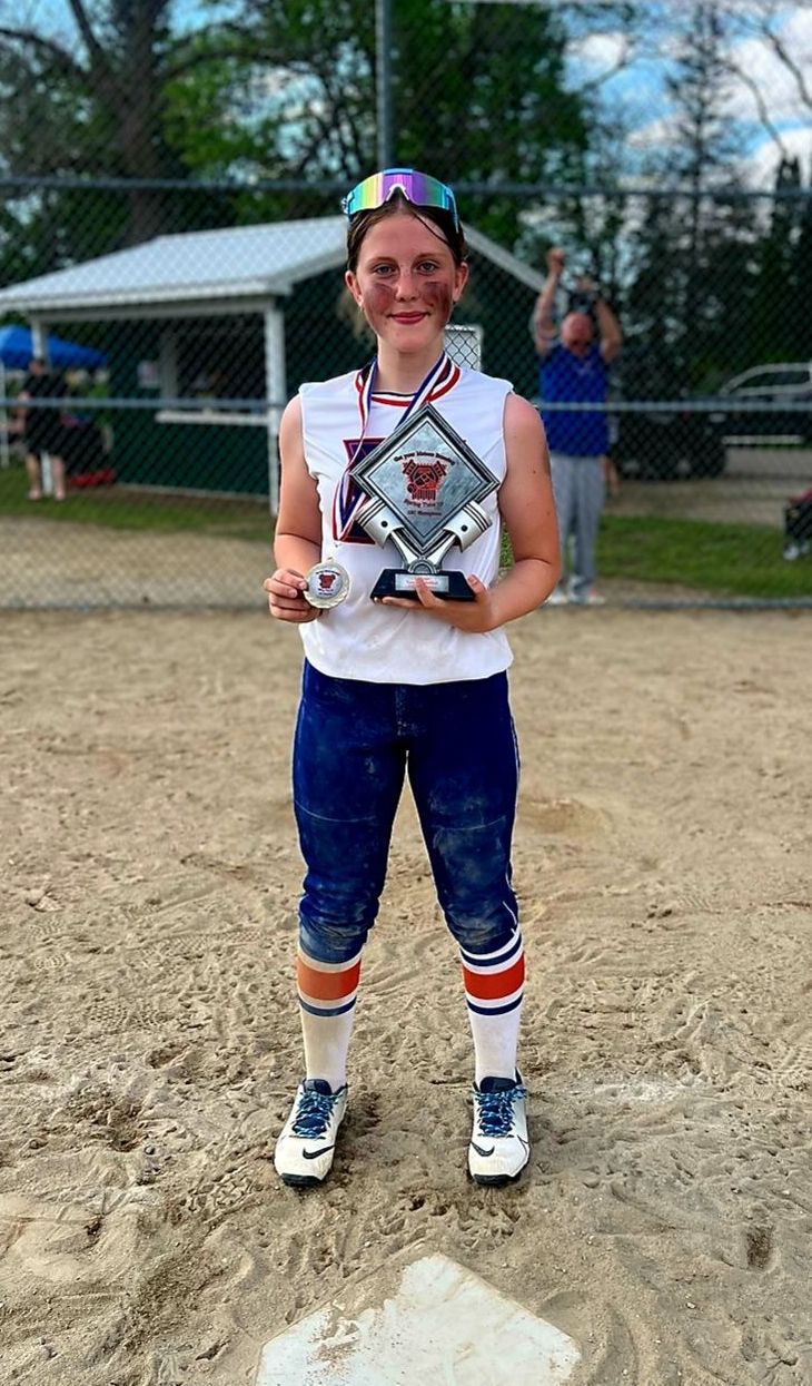 A young girl is standing on a baseball field holding a trophy. Softball and baseball training