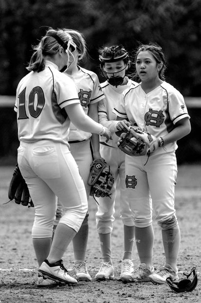 Softball players in uniforms, shaking hands on a field, black and white photo.