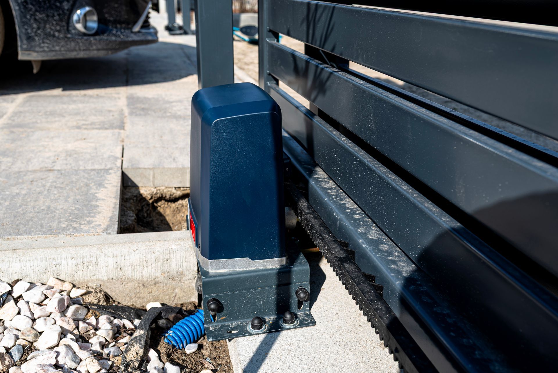 Blue metal post beside a garage door on a concrete driveway, with a white utility meter box nearby