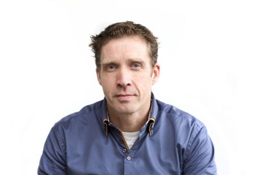 Man in a blue shirt looking at the camera against a white background