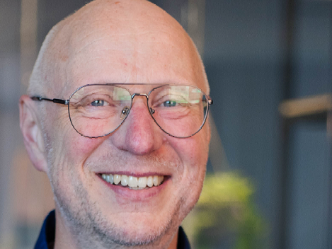Smiling bald man with glasses in a blurred indoor setting