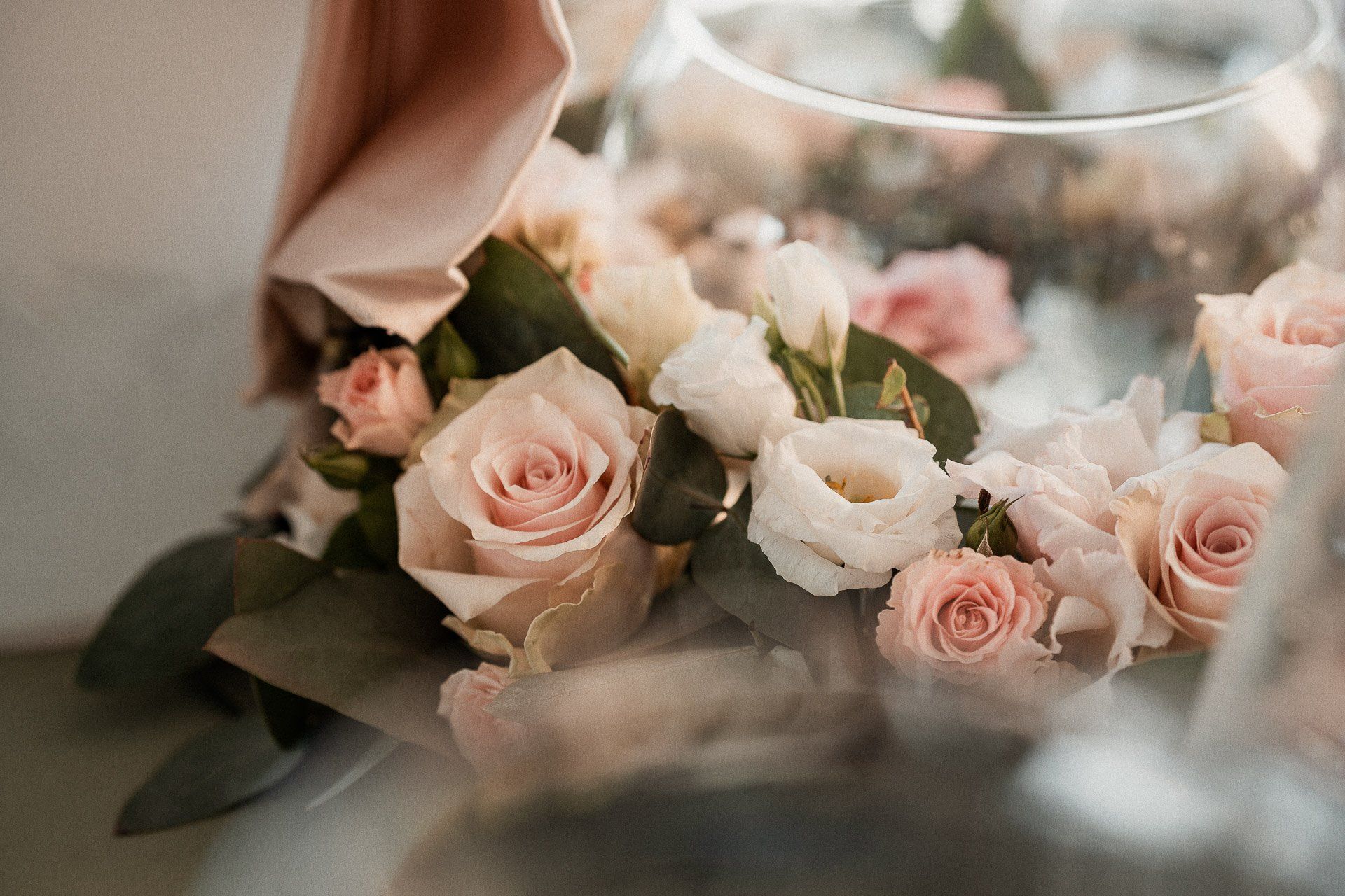 Rose rosa e bianche disposte vicino a una ciotola di vetro, con uno sfondo morbido e sfocato.