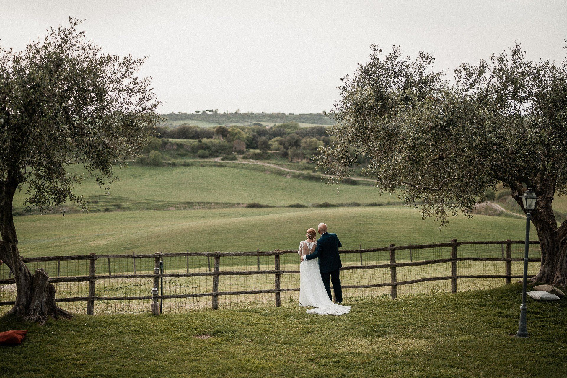 Coppia in abito da sposa con vista sulle dolci colline verdi, incorniciate da ulivi.