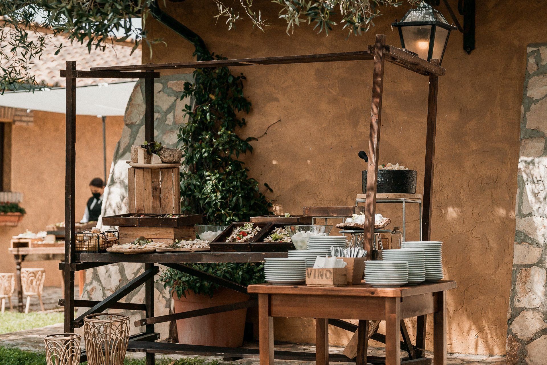 Tavolo da buffet per un evento all'aperto con cibo, torte e piatti impilati.