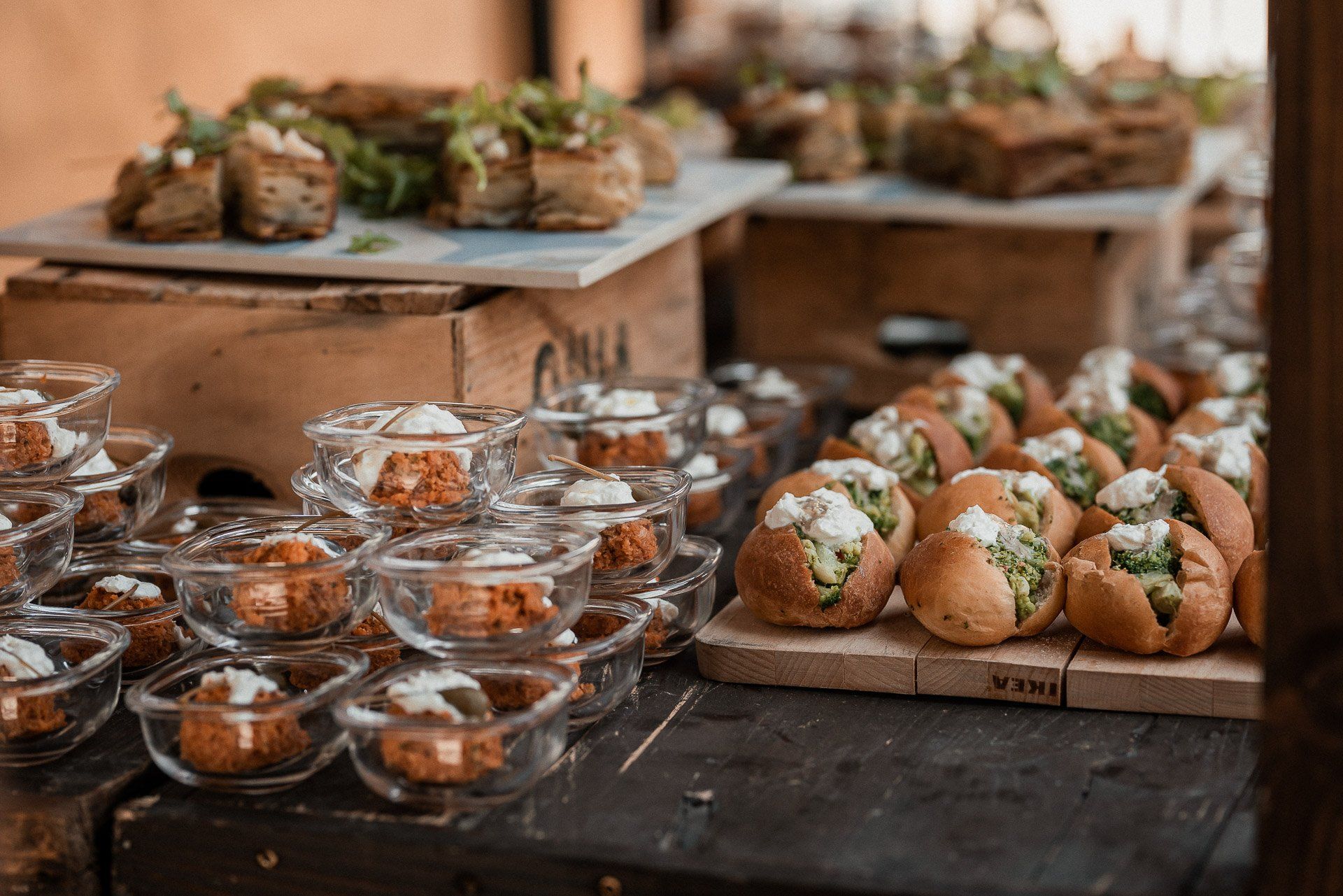 Buffet con numerosi antipasti in esposizione, tra cui ciotole di pane e piccole ciotole di vetro piene di cibo.