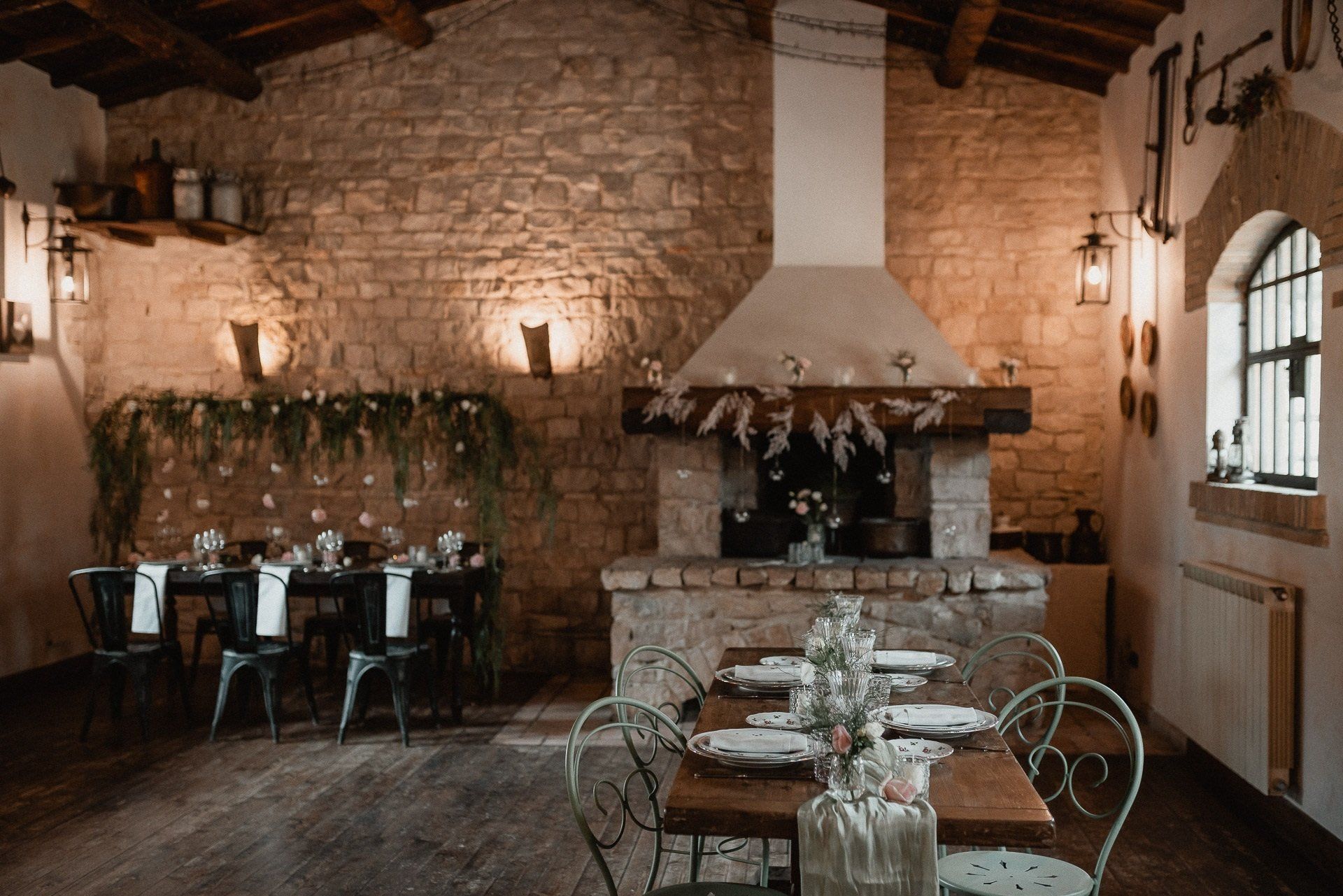 Sala da pranzo rustica con pareti in pietra, camino e tavoli apparecchiati per il pasto.