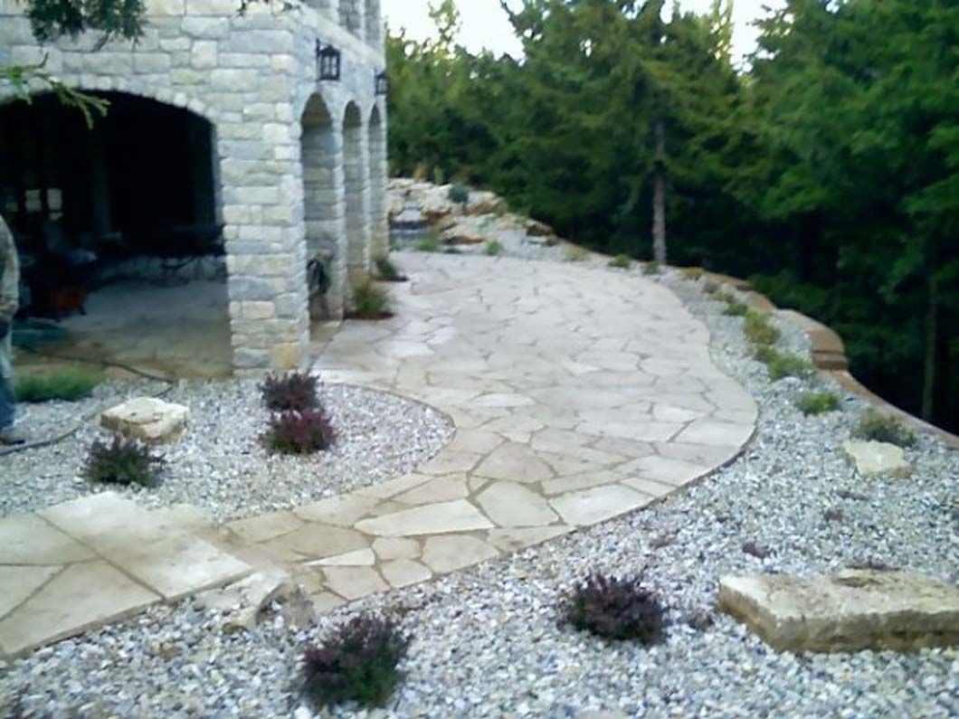 A stone walkway is surrounded by gravel in front of a brick building.
