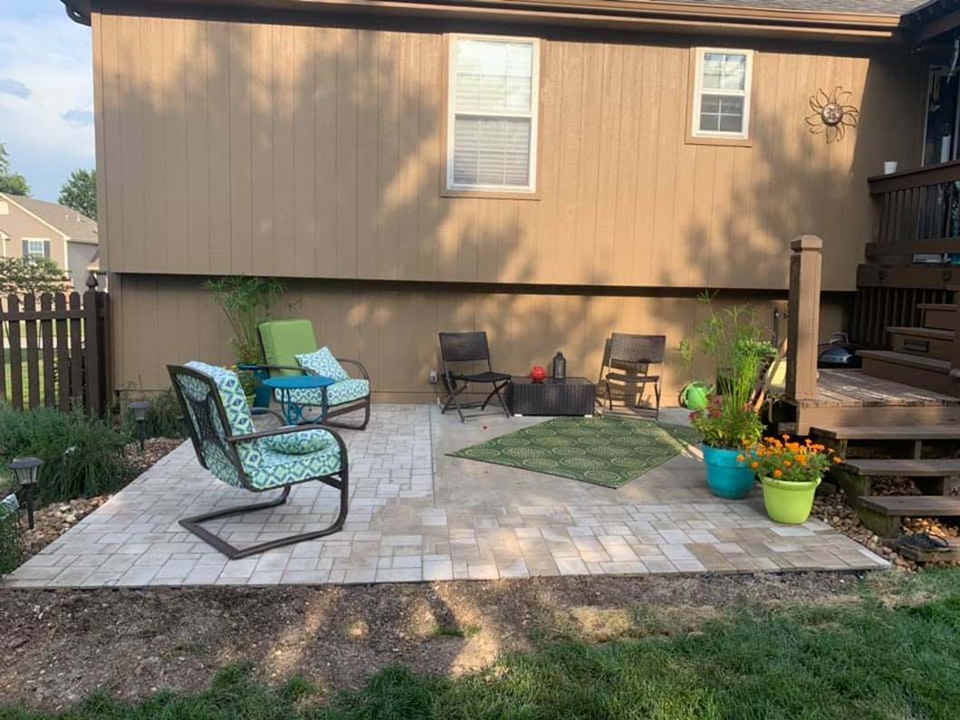 A patio with chairs and a table in front of a house.