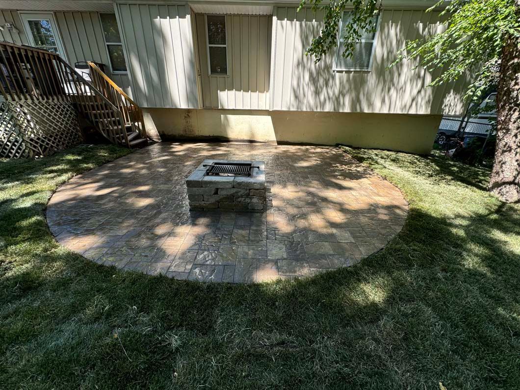 A fire pit is sitting in the middle of a patio in front of a house.