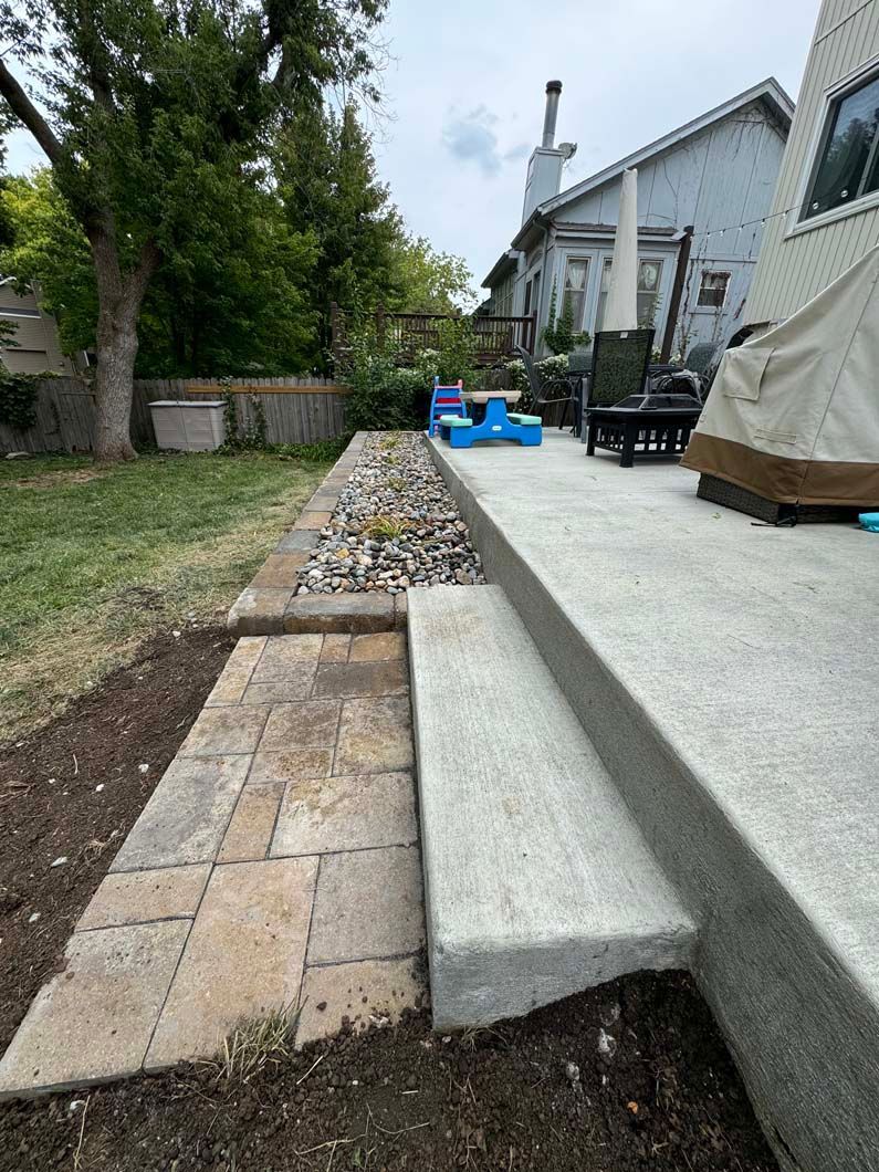 A patio with stairs leading up to it and a picnic table in the backyard.