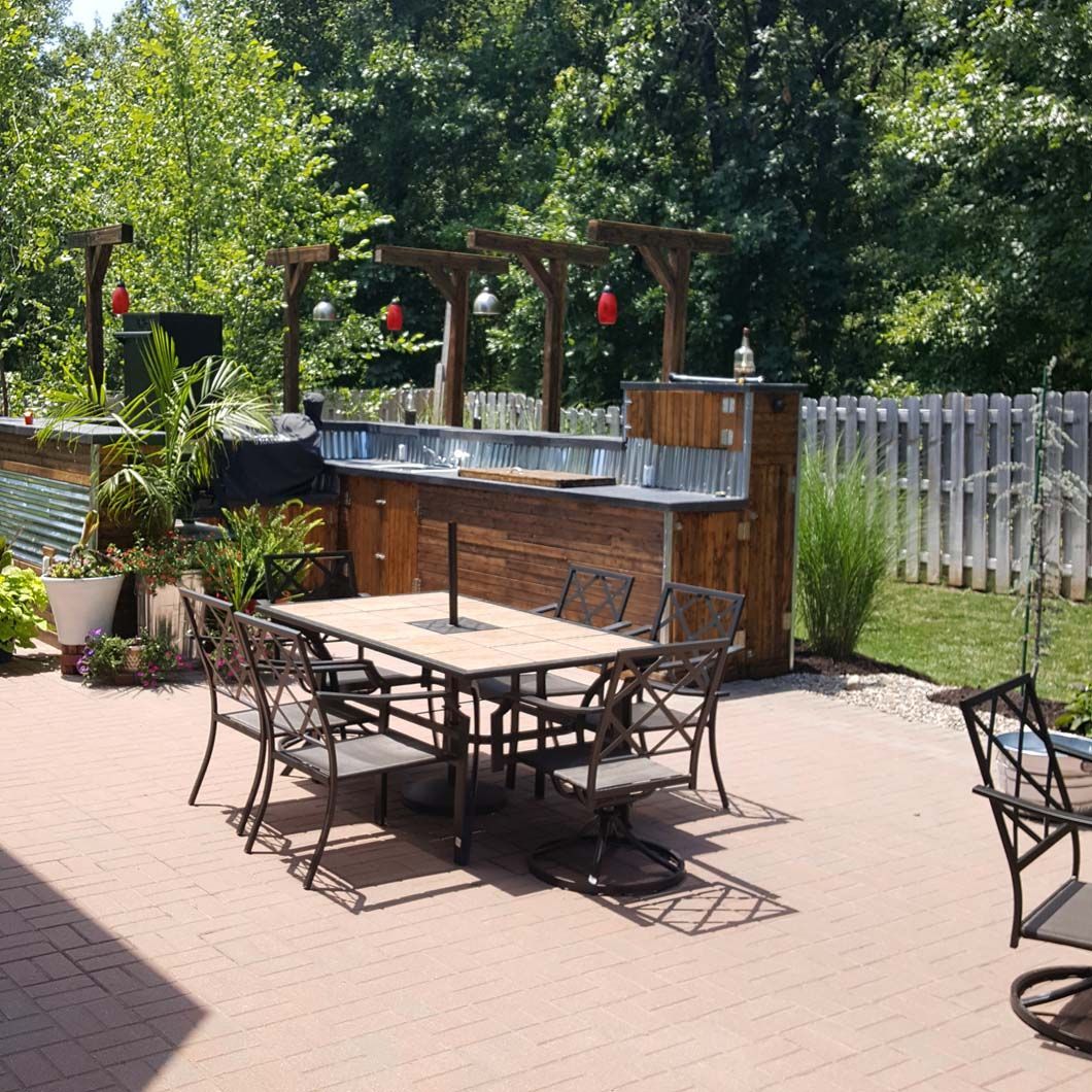 A patio with a table and chairs and a bar in the background