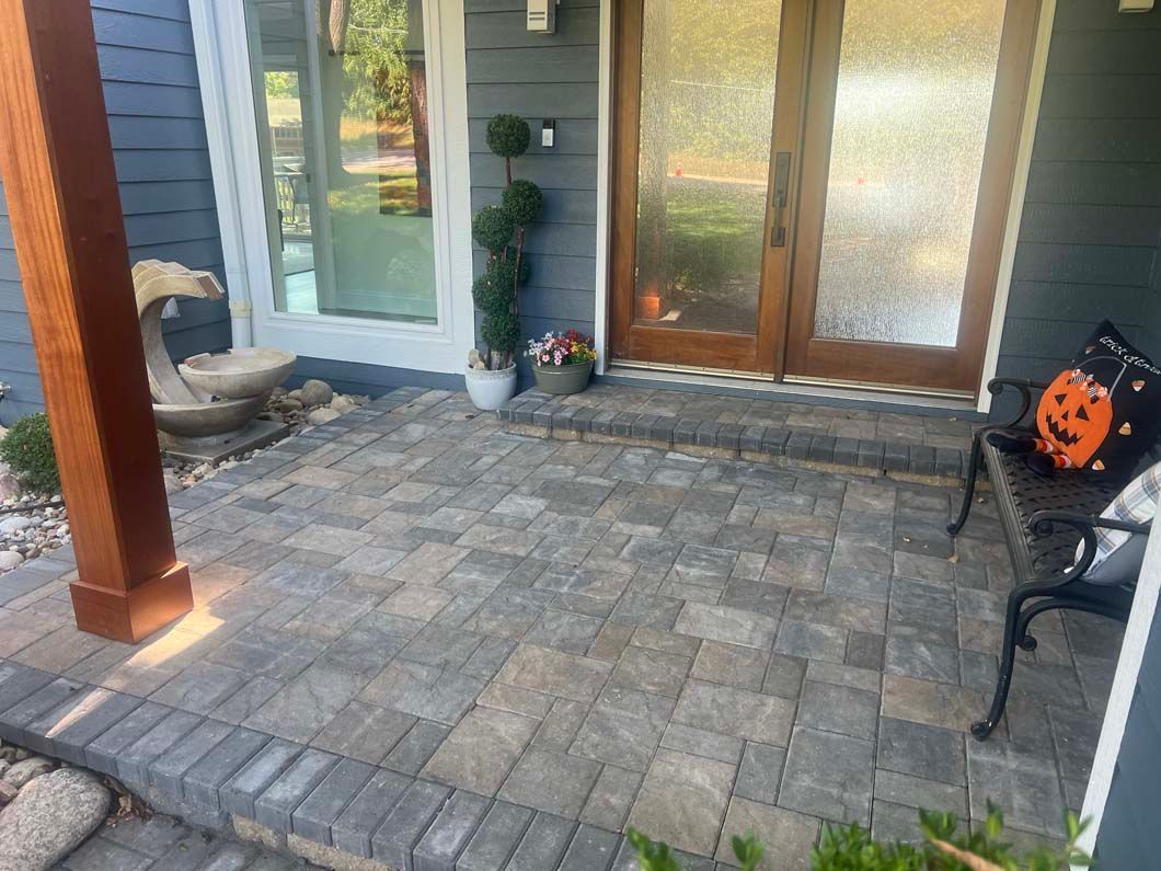 A patio with a bench and a pumpkin on it in front of a house.