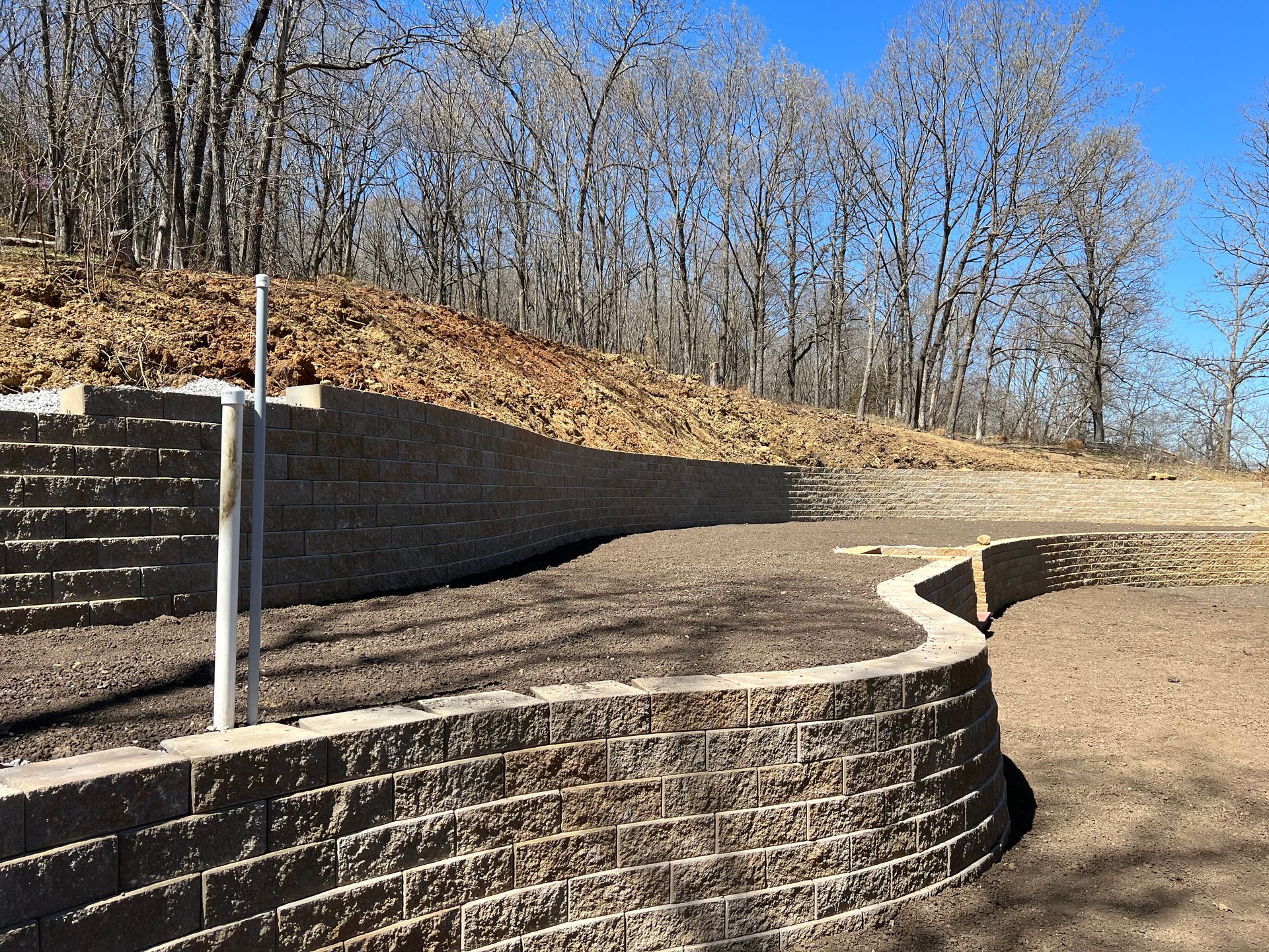 A large brick wall is surrounded by trees on a hillside.