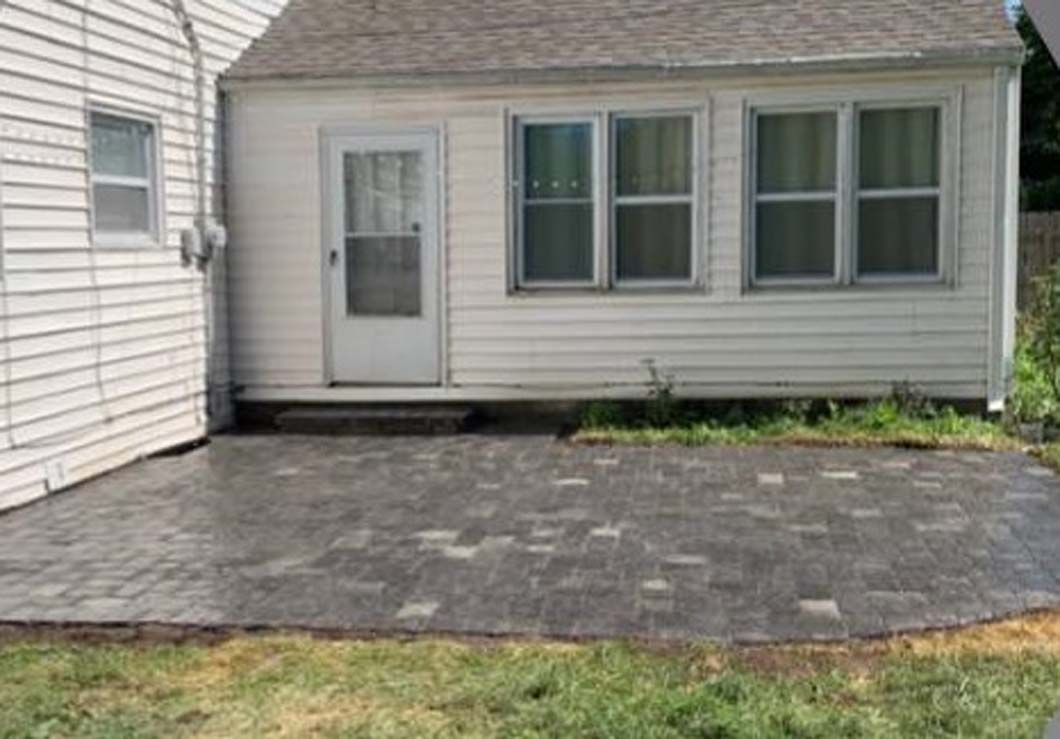 A small white house with a patio in front of it.