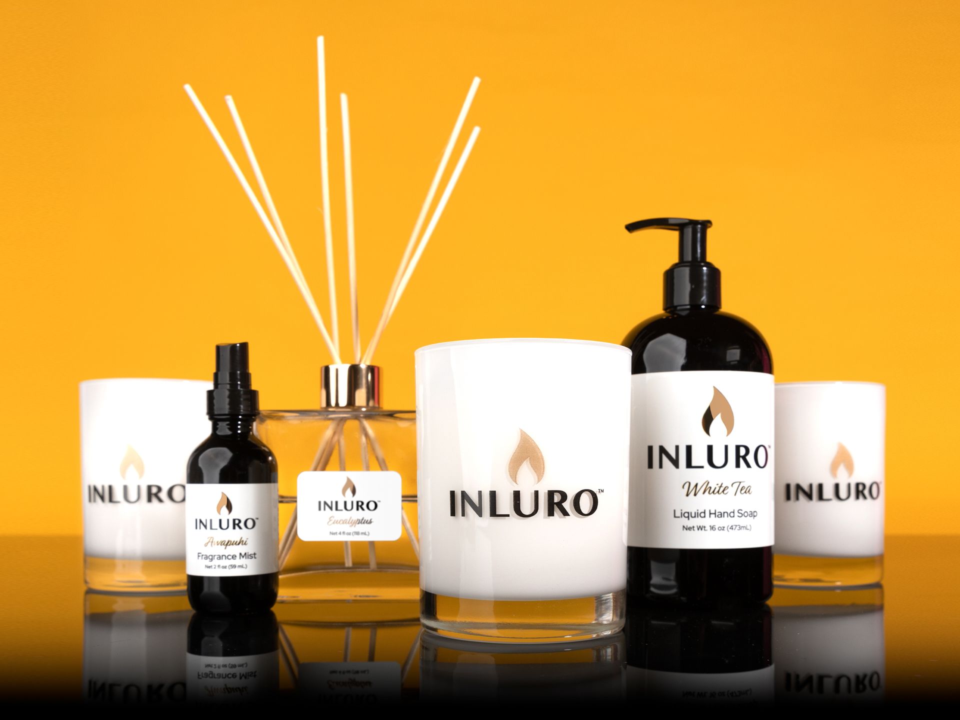 Inluro candle and diffuser set with amber bottles and white packaging on an golden background