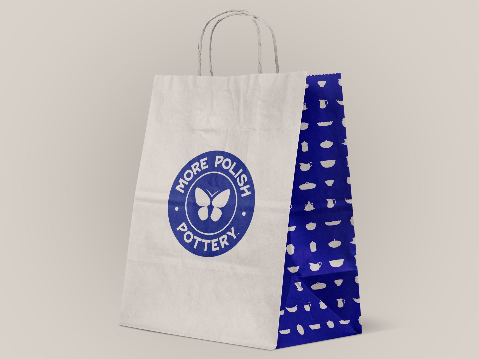 Paper shopping bag with blue circular logo and pattern side panel, on a light background