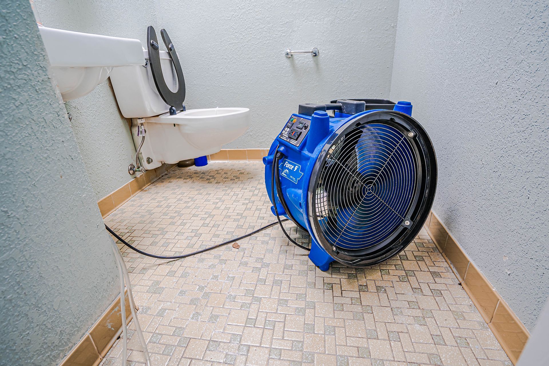 Blue air mover in a small bathroom, drying the floor.