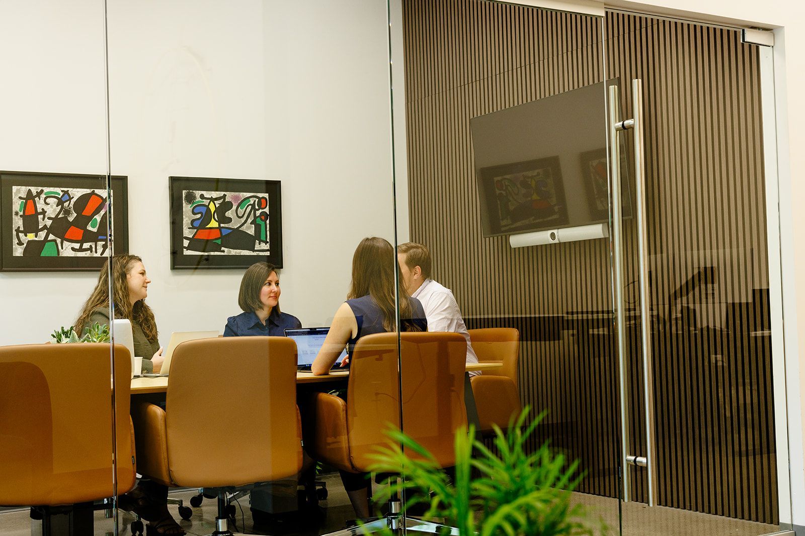 A group of people are sitting around a table with laptops.