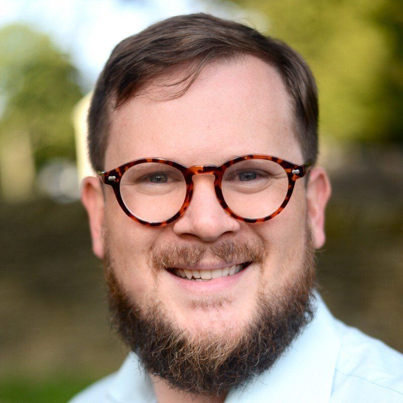 A man with a beard and glasses is smiling for the camera.