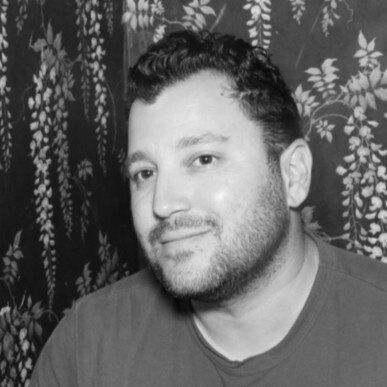 A man with a beard is smiling in a black and white photo