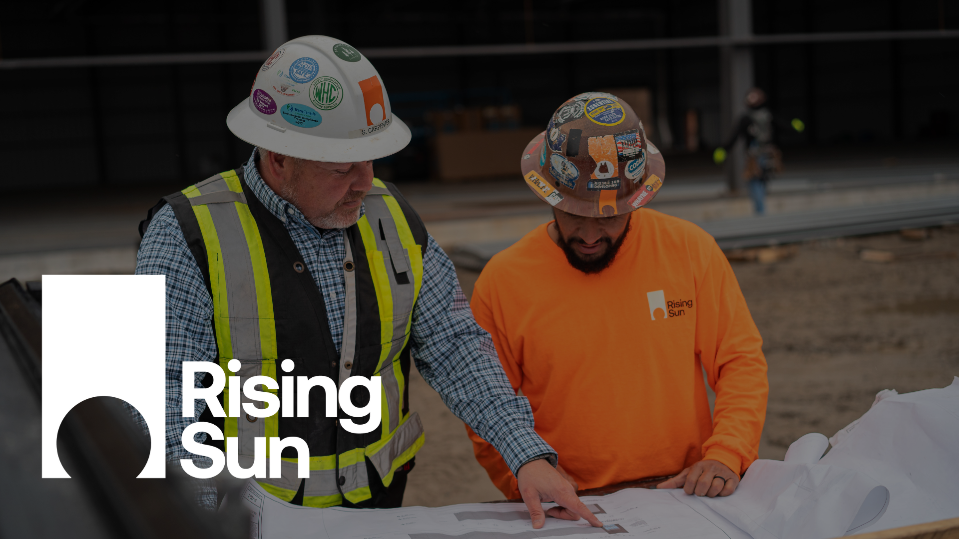 Two construction workers are looking at a blueprint at a construction site.