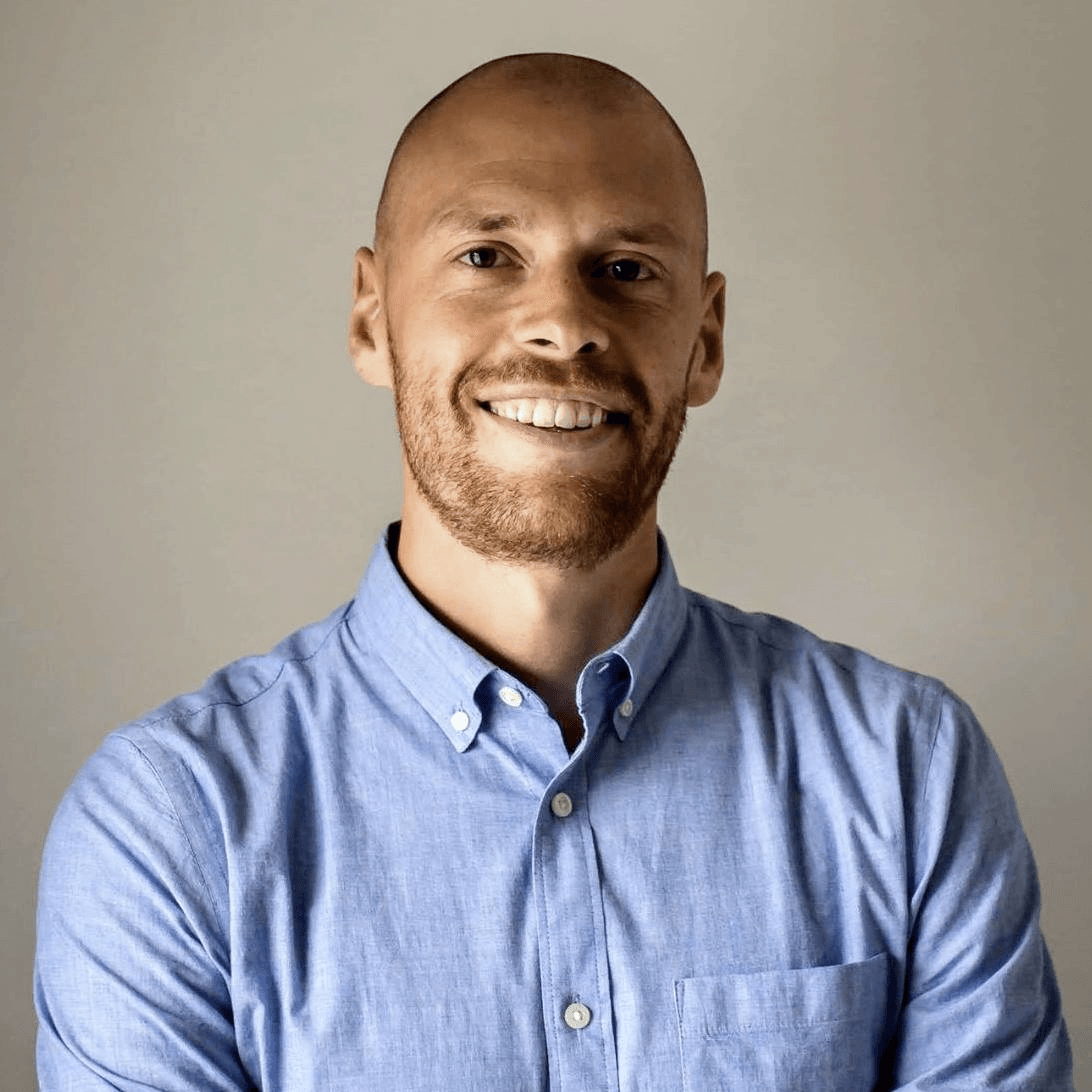 A man with a beard is wearing a blue shirt and smiling