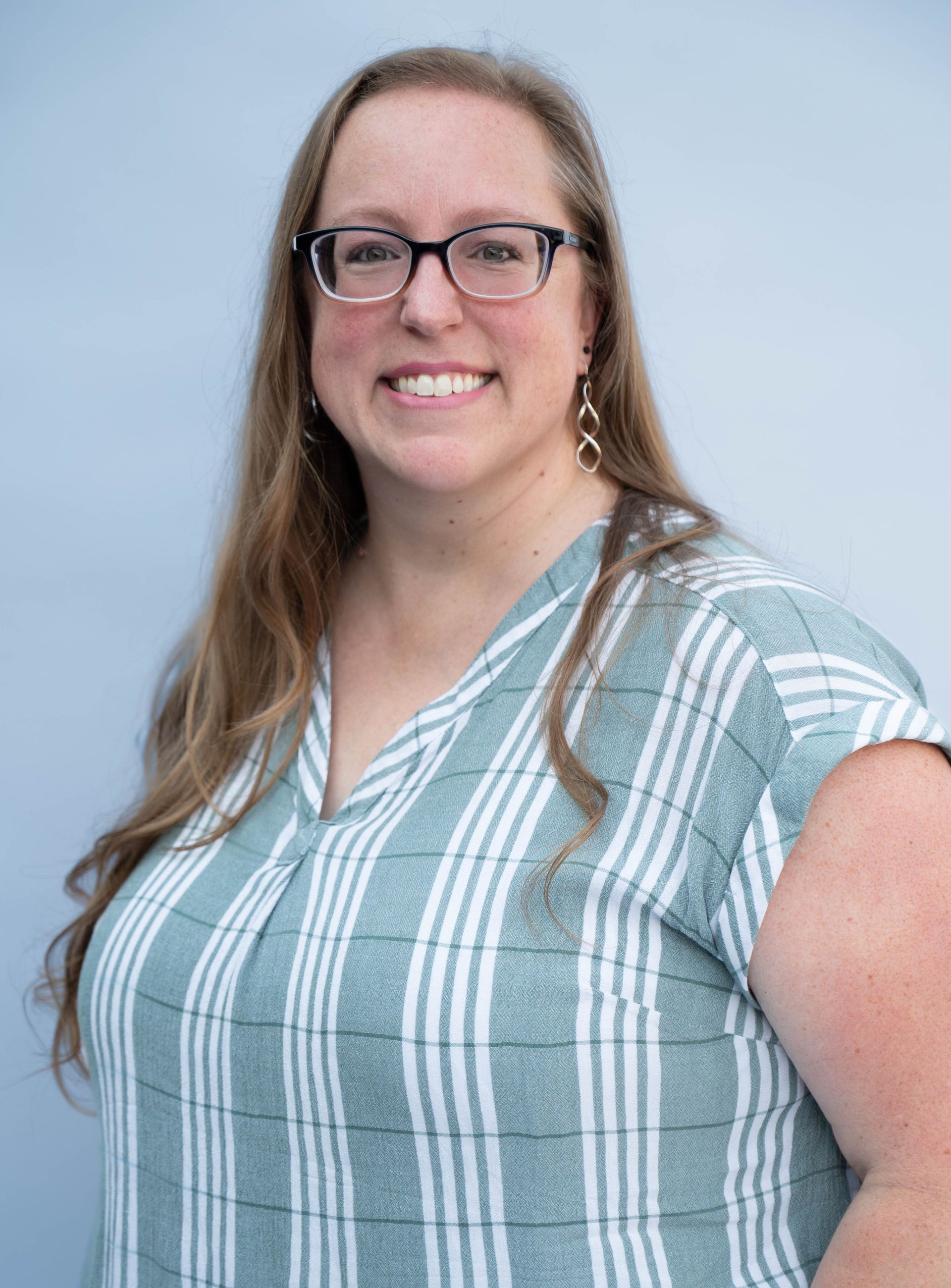 A woman wearing a blue polo shirt is smiling for the camera.