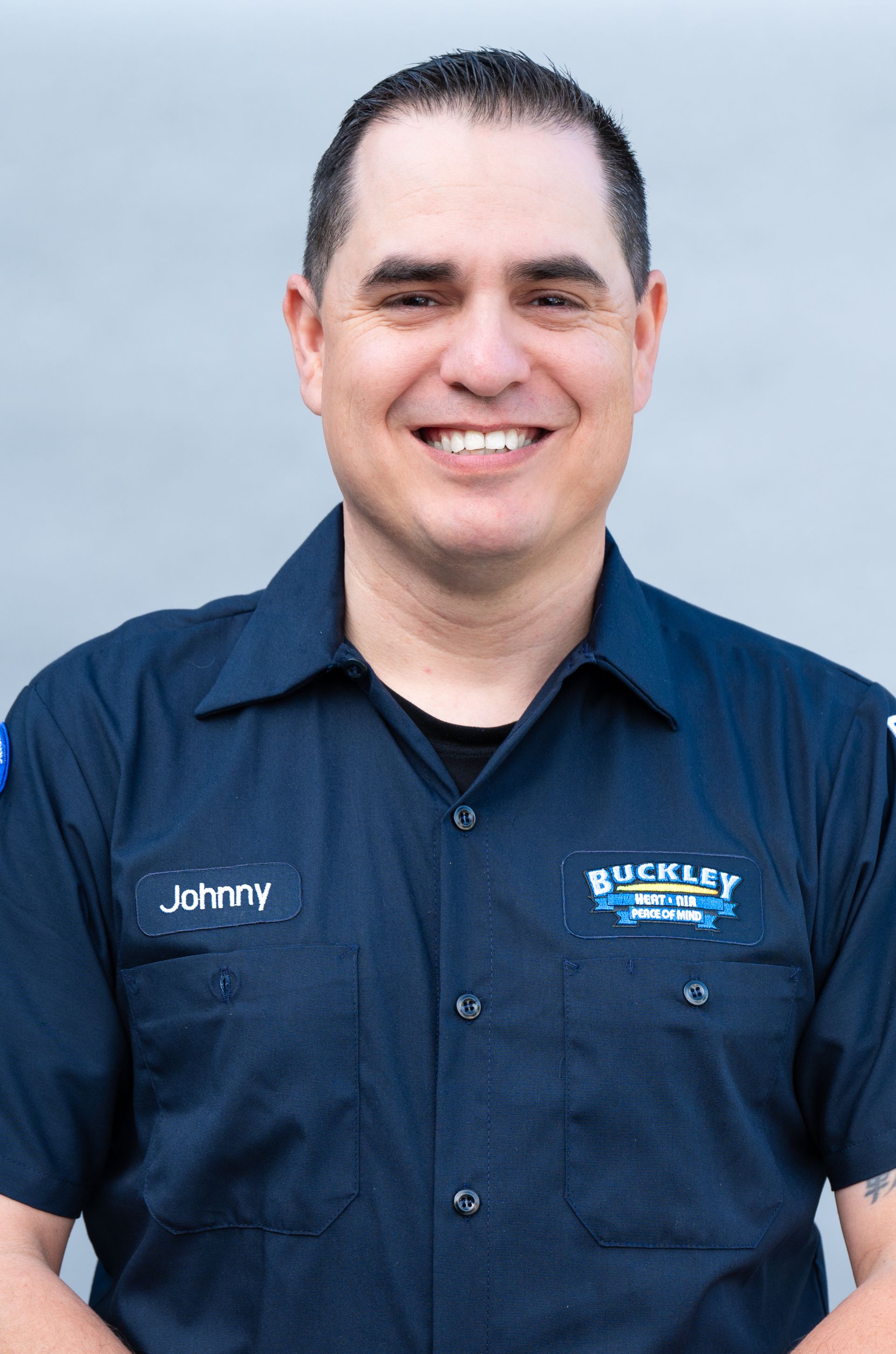 A man wearing a blue shirt with the name johnny on it is smiling for the camera.