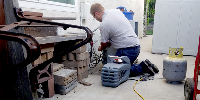 A man is kneeling down while working on a machine.
