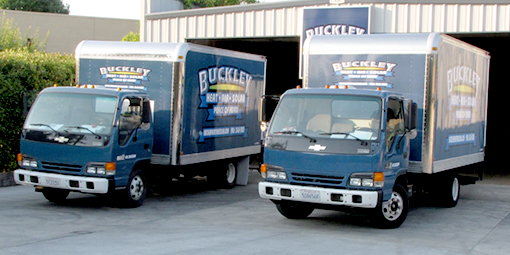 Two buckley trucks are parked in front of a building