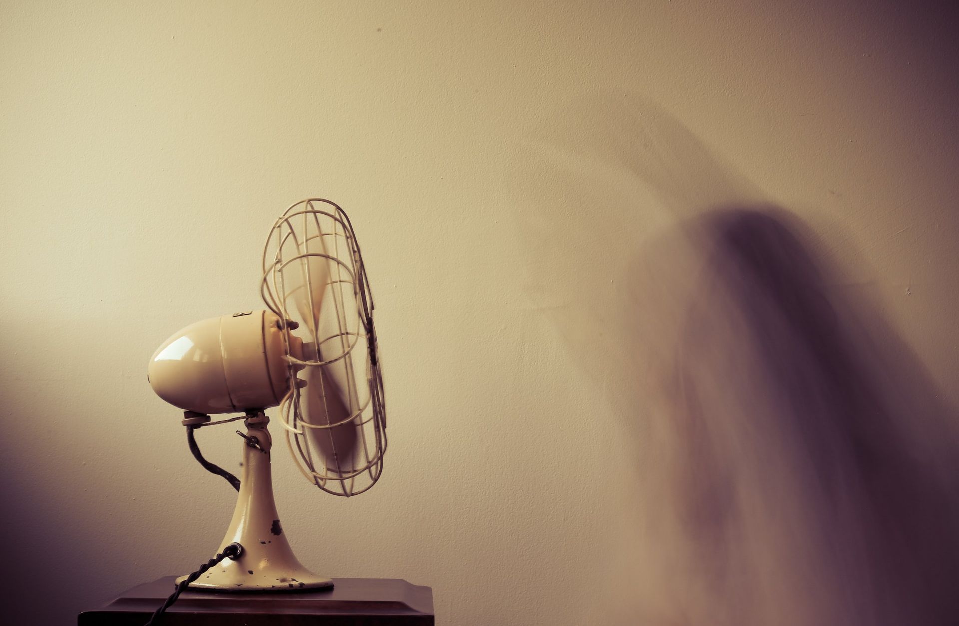 A fan is sitting on a table in front of a wall.