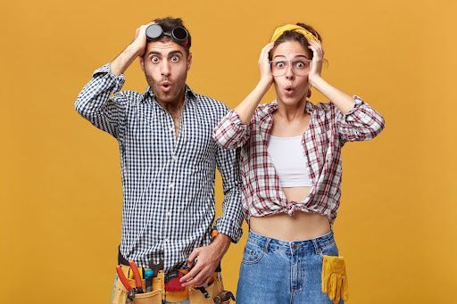 A man and a woman are standing next to each other with their hands on their heads.